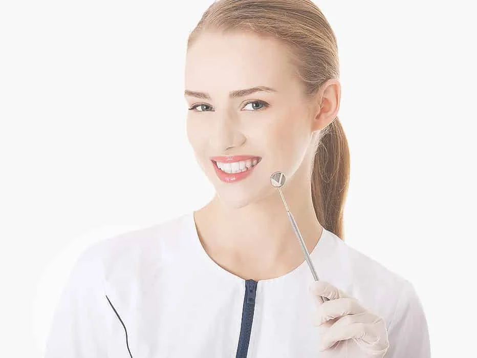 Uśmiechnięta lekarka stomatolog z lusterkiem dentystycznym (zdjęcie poglądowe)